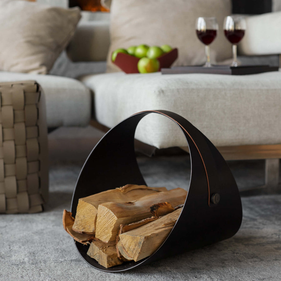 Black leather firewood holder with logs in a living room setting