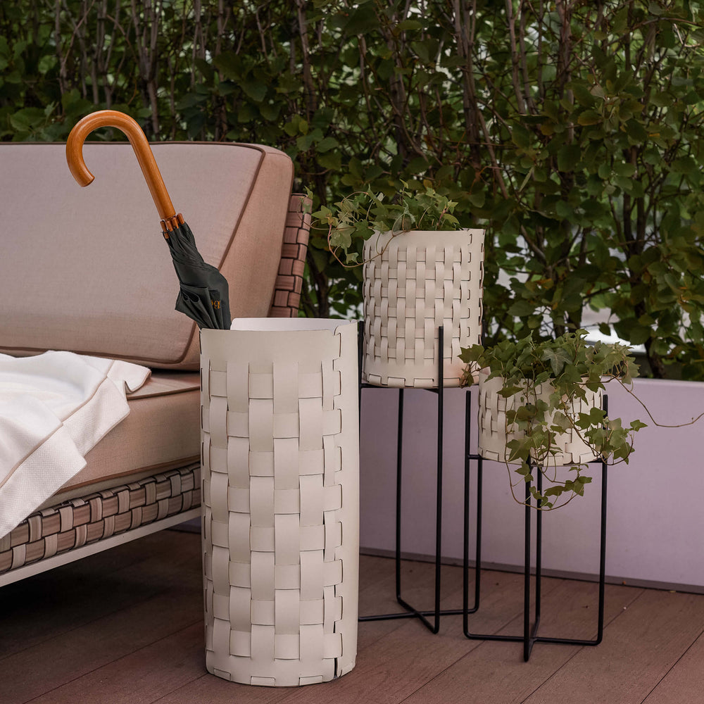 Decorative outdoor scene featuring a woven leather umbrella and various plants.