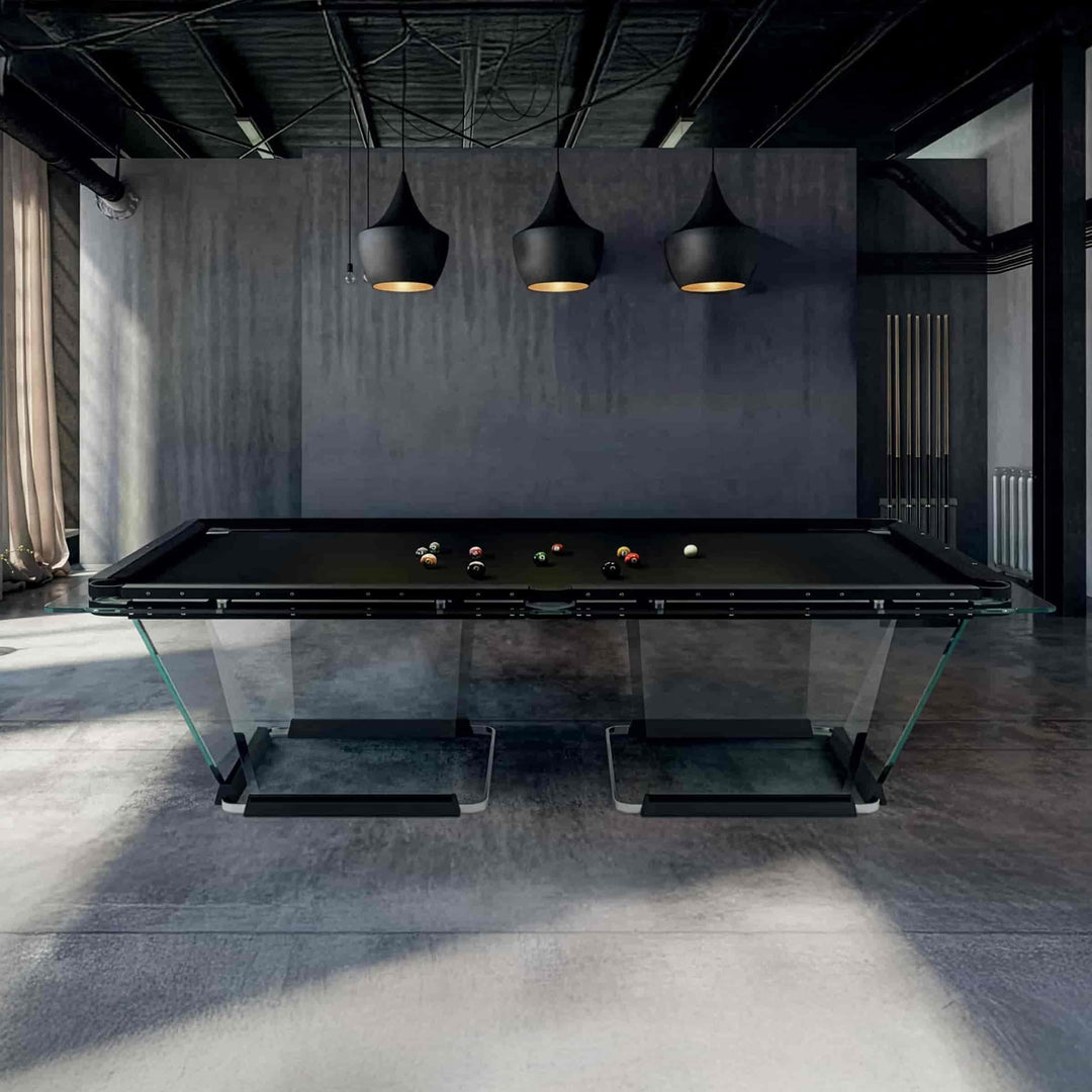 Modern glass pool table in a dimly lit room with dark walls and pendant lights.