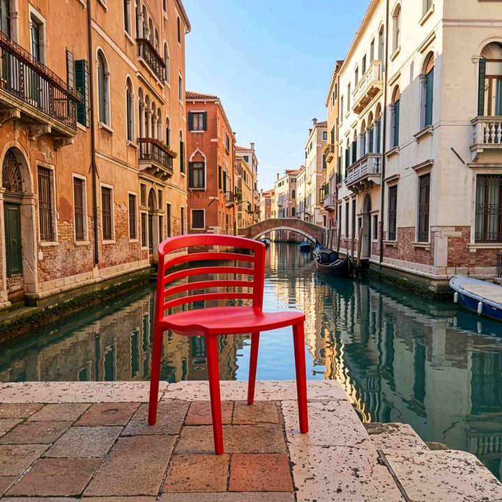 Red chair venezia by bbb italia next to a canal