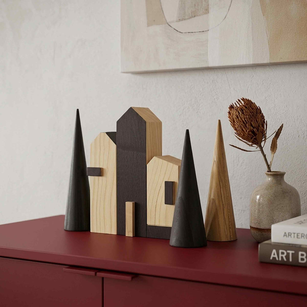 Close-up of Cities Rotterdam wooden houses in natural and dark finishes with cone-shaped trees on a red sideboard