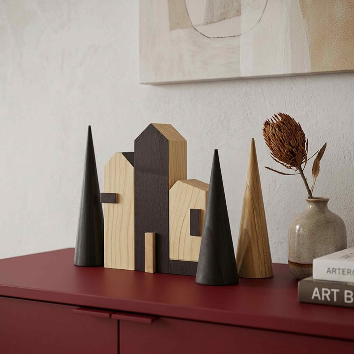 Close-up of Cities Rotterdam wooden houses in natural and dark finishes with cone-shaped trees on a red sideboard