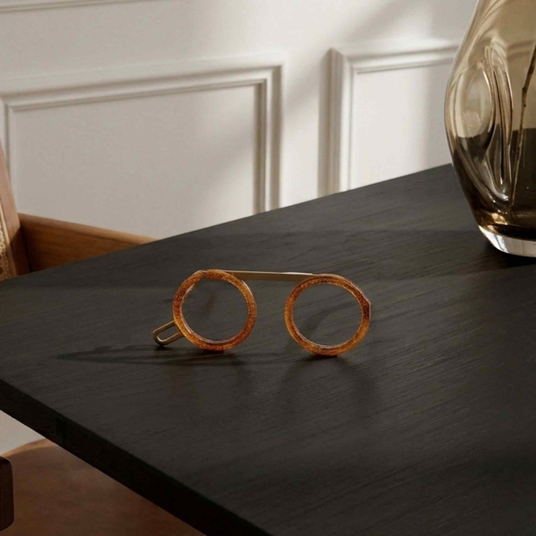 Fassamano Venezia reading glasses with round amber-brown frames resting on a dark wooden table
